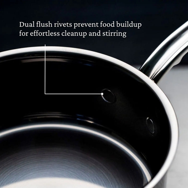 A close-up of the stainless steel saucepan from the NanoBond 10-Piece Titanium Precision Saucepan Cookware Set highlights its dual flush rivets, preventing food buildup for easy cleaning and stirring. NanoBond Technology boosts durability against a softly blurred dark background.