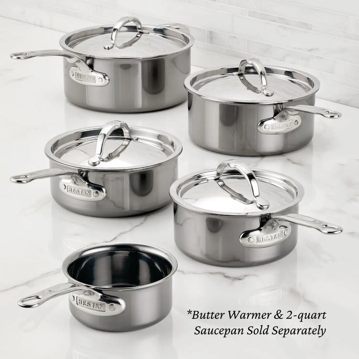 A 10-piece cookware set with titanium precision saucepans, featuring NanoBond Technology, is displayed on a white marble countertop. Each item has a silver handle and NanoBond engraved on the side. Notes indicate two items are sold separately.