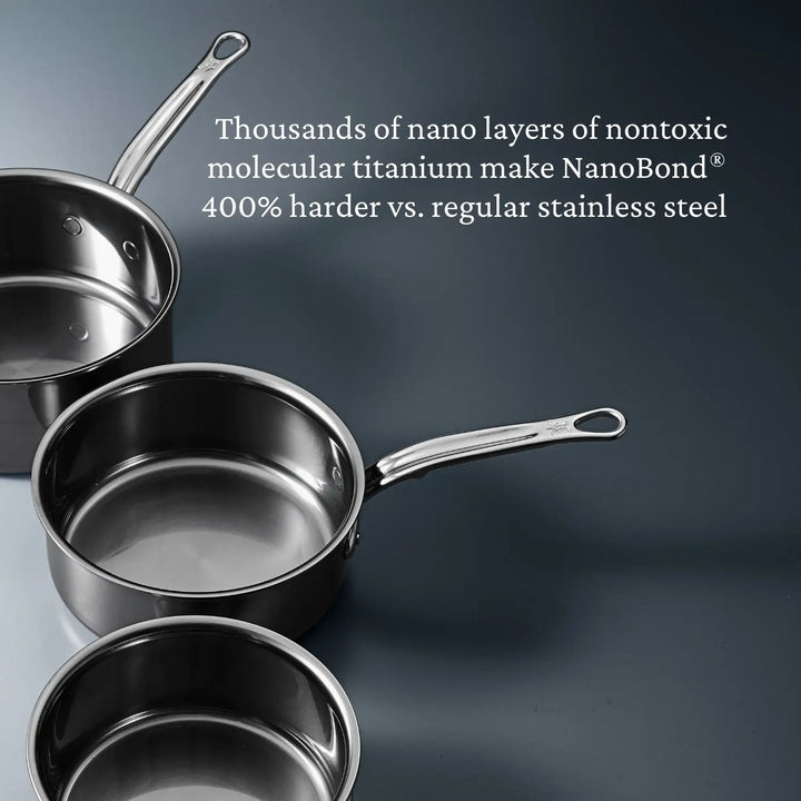 A partial stack of three shiny stainless steel pans with handles sits against a gray background, showcasing NanoBond Technology. This 10-Piece Titanium Precision Saucepan Cookware Set is said to be 400% harder than regular stainless steel.