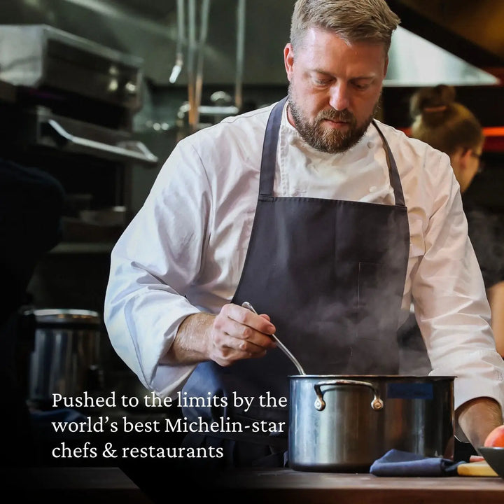 A chef, in a white coat and dark apron, focuses on stirring the pot in a professional kitchen. Text reads, Pushed to the limits by top Michelin-star chefs using NanoBonds 10-Piece Titanium Precision Saucepan Cookware Set for flawless results.