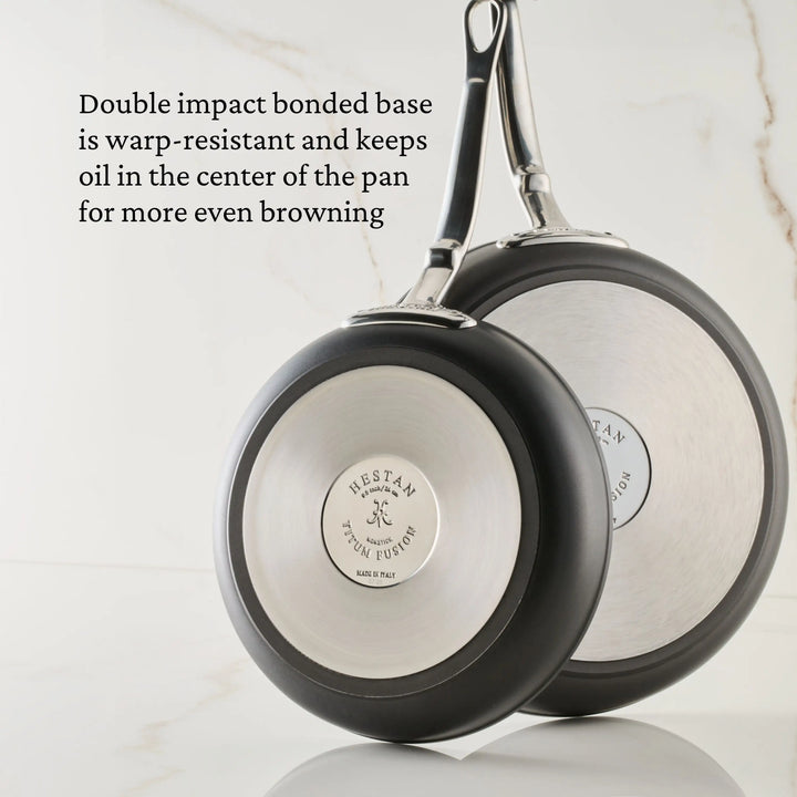 Two TITUM® Fusion TITUM Nonstick Cookware 10-Piece pans, handcrafted in Italy, rest on marble. Their double impact bonded stainless steel base is warp-resistant, induction compatible, and centers oil for even browning.