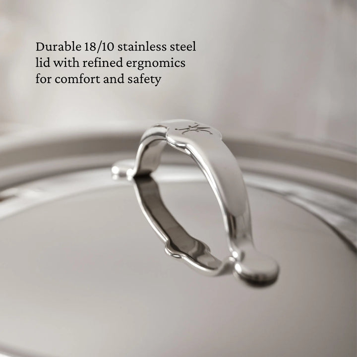 A close-up of the TITUM® Fusion Nonstick Cookware Set lid shows its ergonomic arched handle with engraved detail. The out-of-focus background highlights its durability and induction compatibility.