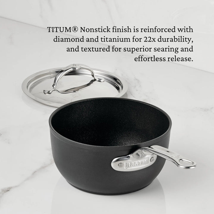 A black TITUM® Fusion Nonstick Saucepan with a shiny metal handle and matching lid sits on white marble. Text above highlights its TITUM® nonstick finish, enhanced durability, textured surface, and Italian handcrafted quality.