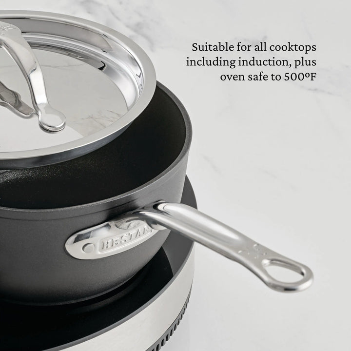 A close-up of the TITUM® Fusion TITUM Nonstick Saucepans with Lids on a stovetop, featuring a metal handle. Induction compatible and oven safe to 500°F, this cookware is nonstick and ideal for all cooktops and daily use.