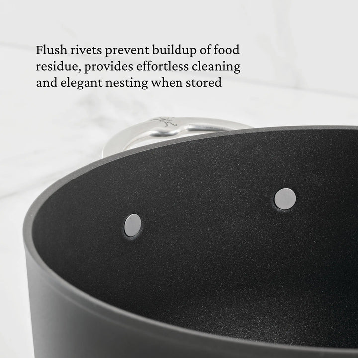 Close-up of the TITUM® Fusion TITUM Nonstick Stock Pot with Lid, 8-Quart, featuring two flush rivets on its silver handle to prevent food buildup, simplify cleaning, and enable elegant nesting for storage.
