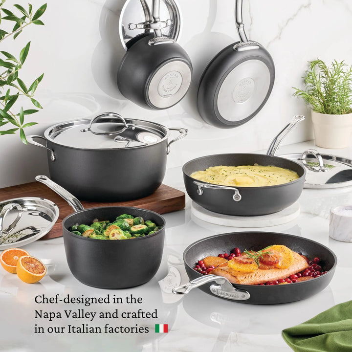 The TITUM® Fusion Nonstick Essential Pan with Lid, 4.5-Quart, is displayed on a white kitchen counter. Handcrafted in Italy and designed for chefs in Napa Valley, this black nonstick cookware blends chef-quality and modern style.