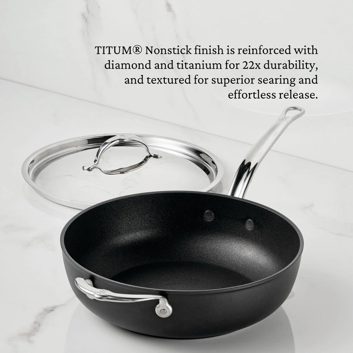 A sleek black TITUM® Fusion Essential Pan with a shiny metal handle and glass lid sits on white marble. Text highlights its durable, textured TITUM® nonstick finish for easy release. Handcrafted in Italy, this 4.5-quart pan is premium cookware.