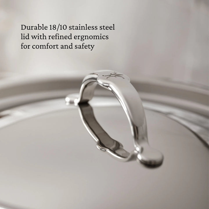 Close-up of the TITUM® Fusion TITUM Nonstick Skillet with Lid, 11-Inch, featuring a shiny, curved handle. Text highlights its durable 18/10 stainless steel build and ergonomic design for comfort and safety.