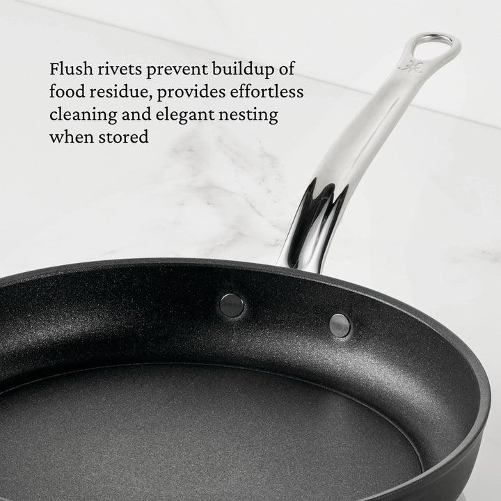 The TITUM® Fusion TITUM Nonstick Skillet with Lid, 11-Inch, handcrafted in Italy, features a metal handle and flush interior rivets for easy cleaning and compact storage. It’s shown on a white marble surface.