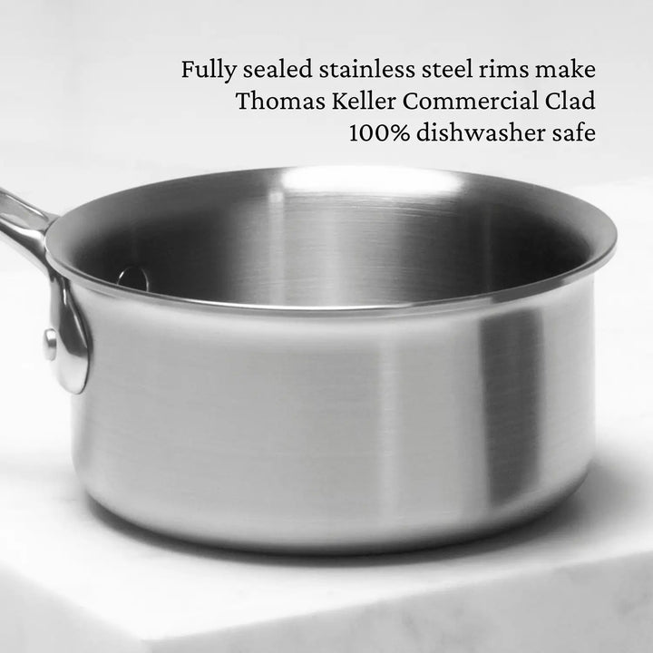 A Thomas Keller Insignia Commercial Clad Stainless Steel 0.75-Quart Butter Warmer with a handle is on a white surface, showcasing its kitchen-proven stainless steel rims that make it 100% dishwasher safe.