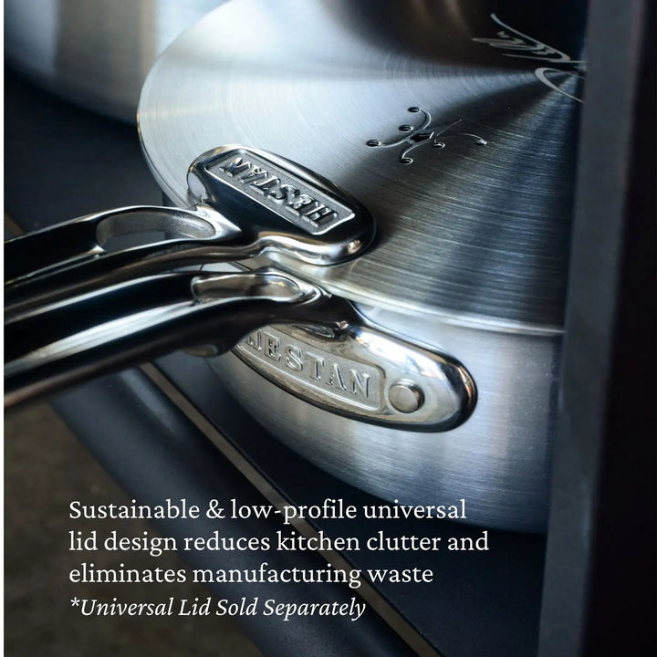 A close-up shows stacked Thomas Keller Insignia Commercial Clad Stainless Steel Saucepans with engraved logos on the handles, highlighting their chef-designed, sustainable, low-profile lids for exceptional results. The versatile lid is sold separately.