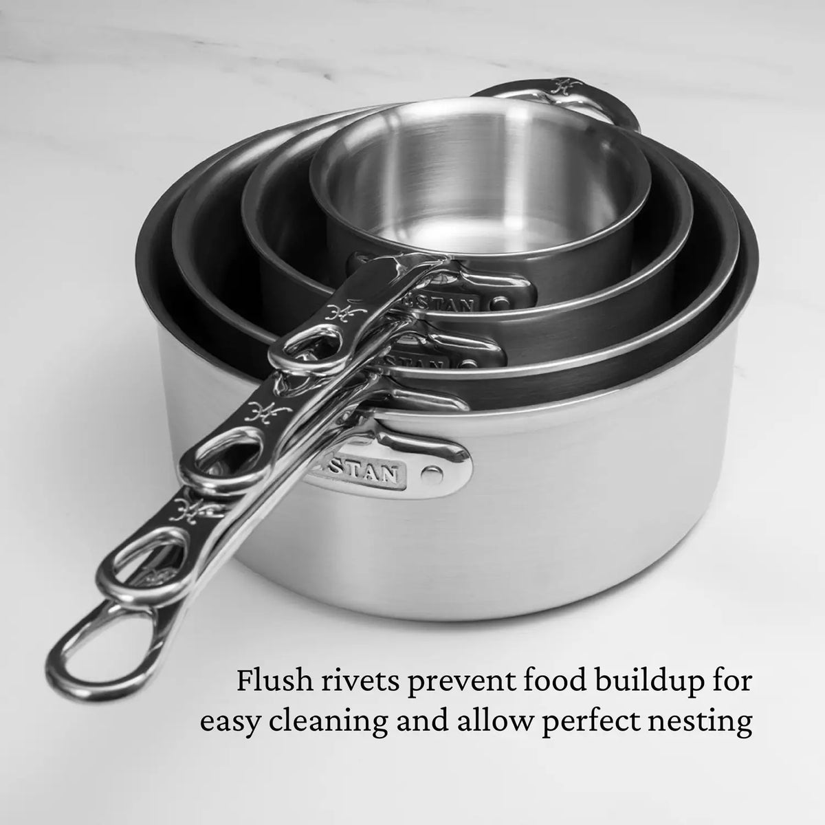 Four Thomas Keller Commercial Clad Stainless Steel Saucepans of varying sizes nested together, with flush rivets on the handles for easy cleaning and enhanced professional culinary performance.