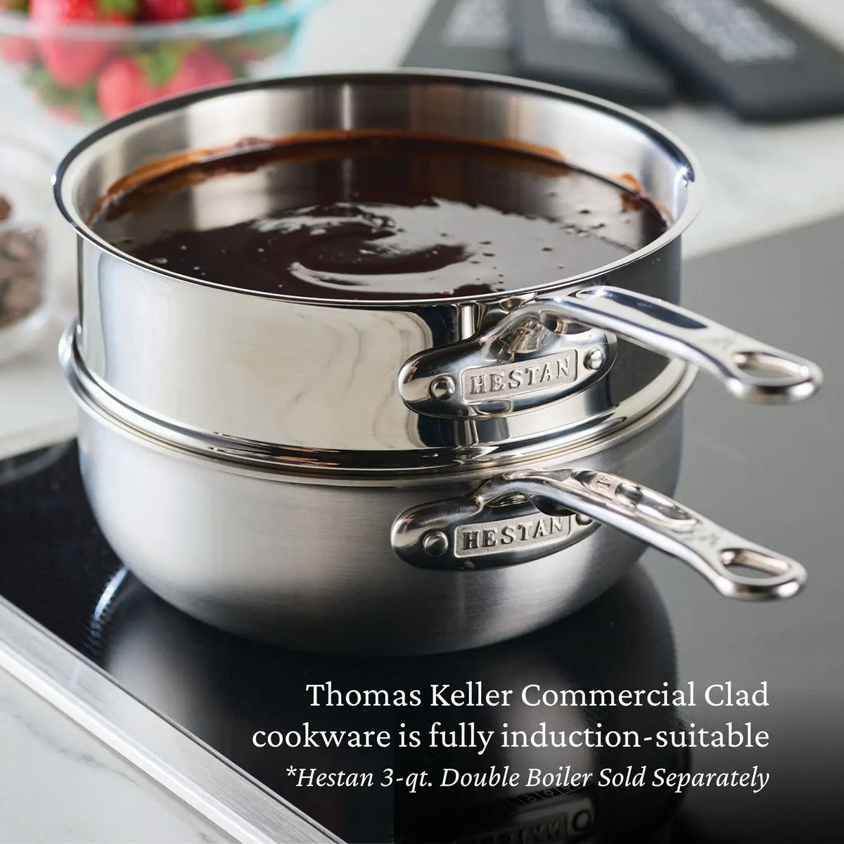 A Thomas Keller Commercial Clad Stainless Steel 2-Quart Saucier sits atop an induction cooktop melting chocolate. The tri-ply construction ensures professional performance and is fully induction-suitable.