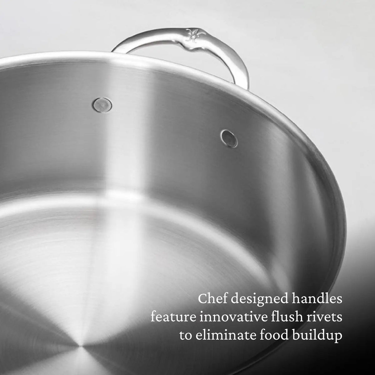 A close-up of the Thomas Keller Commercial Clad Stainless Steel Stock Pot, featuring chef-designed handles with innovative flush rivets to eliminate food buildup.