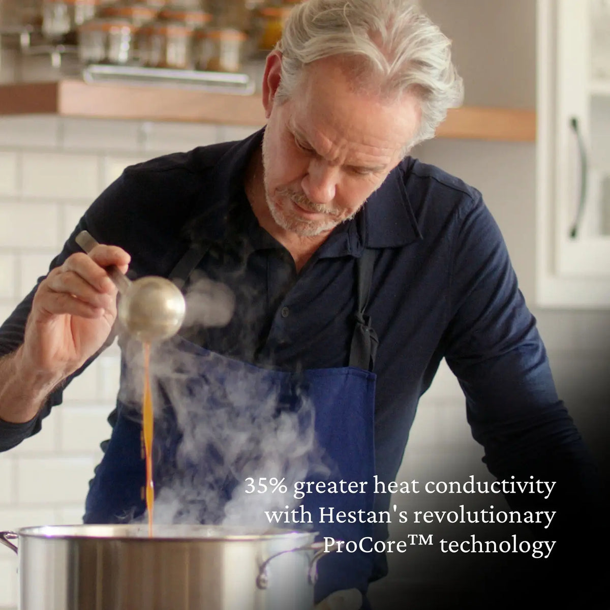 A man in a dark apron ladles liquid from a steaming Thomas Keller Commercial Clad Stainless Steel Stock Pot. Text reads: 35% greater heat conductivity with revolutionary ProCore™ for professional culinary performance.