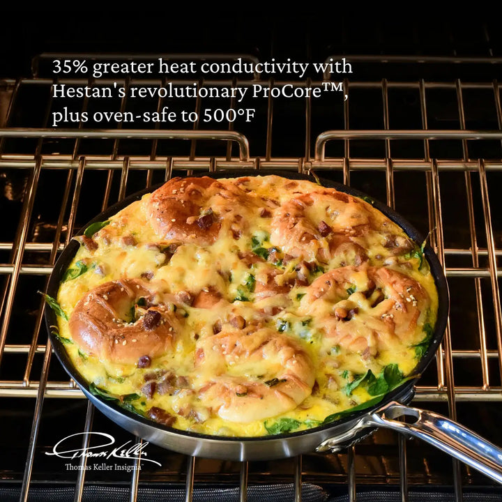 Image features 8.5-inch Thomas Keller TITUM Nonstick Skillet in the oven with a bagel frittata cooked in the skillet. Text on image reads: "35% greater heat conductivity with Hestan's revolutionary ProCore™, plus oven-safe to 500°F".