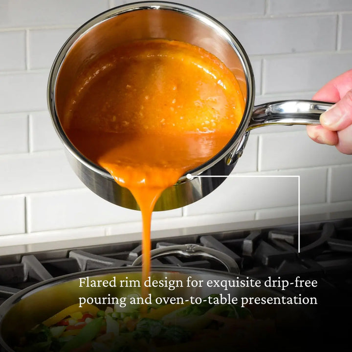 A ProBond Professional Clad Stainless Steel Saucepan with a stainless steel handle pours orange sauce onto vegetables in a pot. The text reads, Flared rim design for exquisite drip-free pouring and oven-to-table presentation. Its tri-ply aluminum core construction ensures durability against a white tile backsplash.