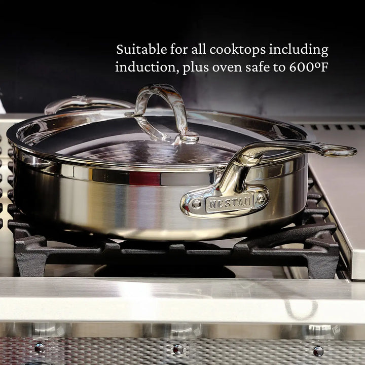 A ProBond Professional Clad Stainless Steel Covered Sauté Pan with handles and a glass lid is on the stovetop. The text above reads, Suitable for all cooktops, including induction, plus oven safe to 600°F. Its tri-ply body showcases the ProBond name on the side.