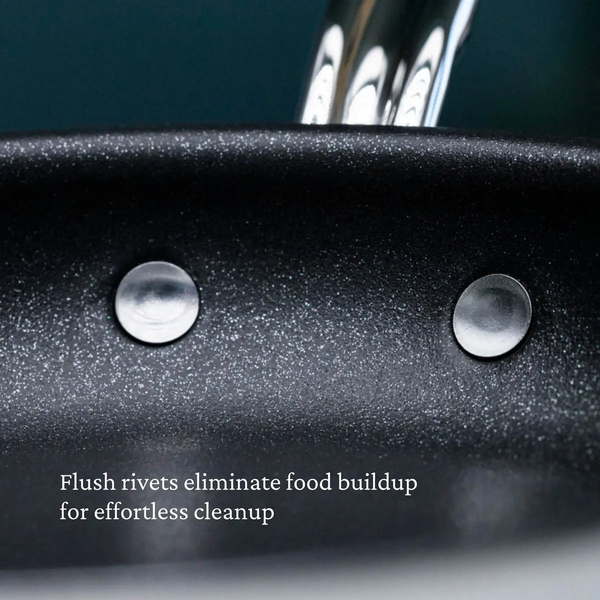 Close-up of the inside of a ProBond Professional Clad Stainless Steel TITUM® Nonstick Skillet shows two metal flush rivets. The speckled surface is text-labeled, Flush rivets eliminate food buildup for effortless cleanup.