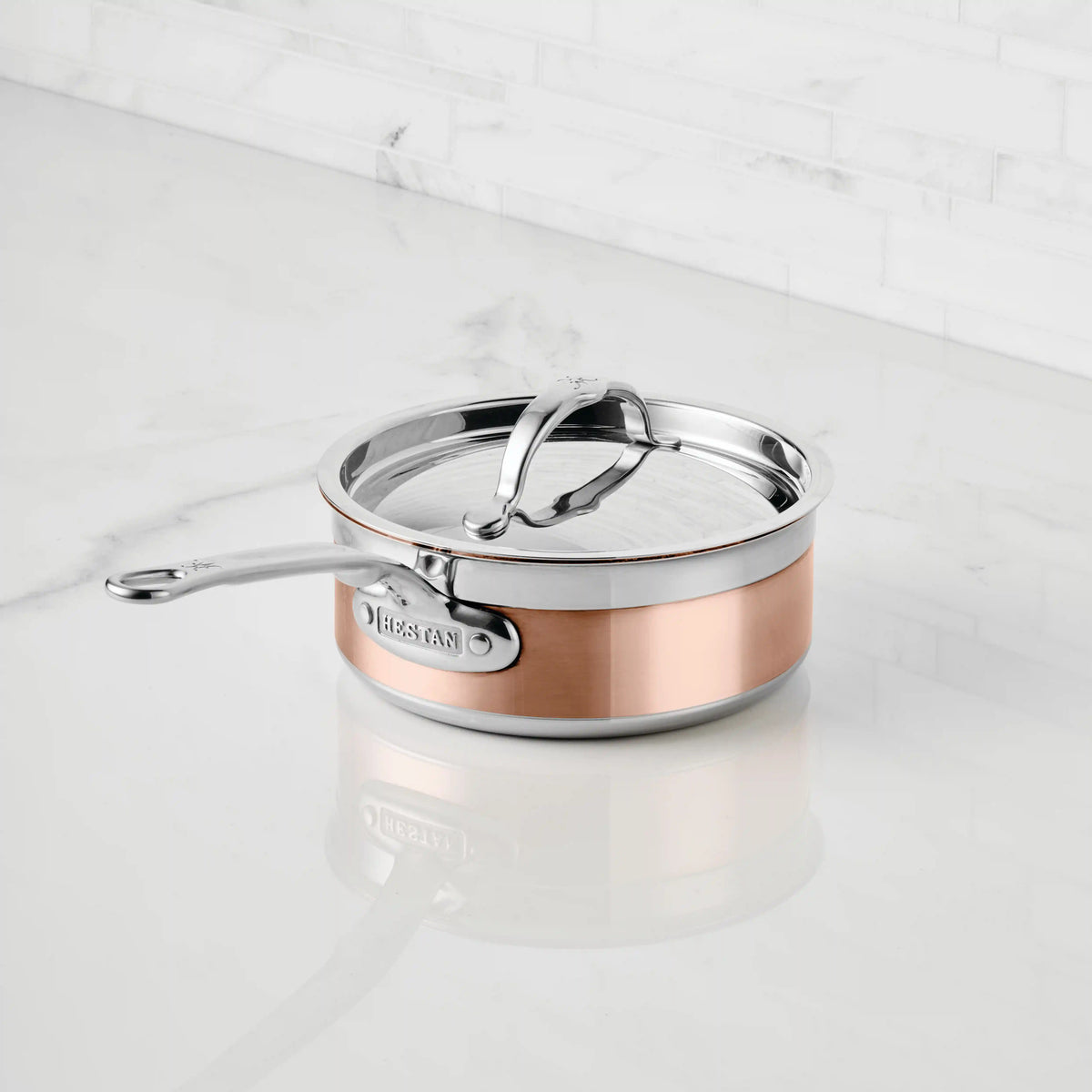 A CopperBond Copper Induction Saucepan with a stainless steel handle rests on a white marble countertop, the CopperBond brand name clearly visible on the side.