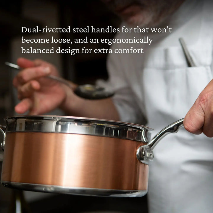 A person in a chefs uniform scoops food with a spoon from a CopperBond Copper Induction Saucepan. Text describes the pan: Dual-riveted steel handles that wont become loose, and an ergonomically balanced design for extra comfort.