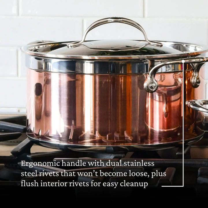 The CopperBond 6-Quart Copper Induction Stock Pot stands on a stovetop with an ergonomic handle and dual stainless steel rivets. Flush interior rivets ensure durability and easy cleanup. Its 5-ply design suits an induction cooktop, beautifully contrasting the white tiled backsplash.