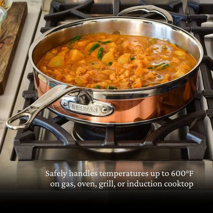 A CopperBond Copper Induction Sauté with Lid, 3.5-Quart pan simmers a tomato-based stew of chicken, potatoes, and green beans on the stovetop. The 5-ply construction safely withstands up to 600°F on gas, oven, grill, or induction cooktop.