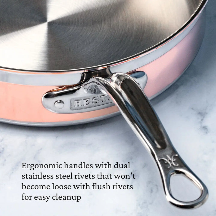 A close-up of the CopperBond Copper Induction Sauté with Lid, 3.5-Quart, featuring a stainless steel handle with dual rivets and an engraving. Text beside reads: Ergonomic handles with secure rivets, 5-ply construction, induction compatible for easy cleanup.