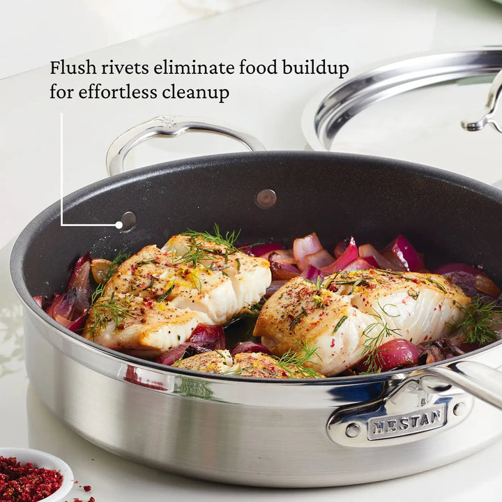 A ProBond Professional Clad Stainless Steel TITUM® Nonstick pan showcases cooked chicken, onions, and herbs. It features flush rivets for easy cleaning. A metal lid highlights this exceptional piece of the 10-piece Hestan cookware set.