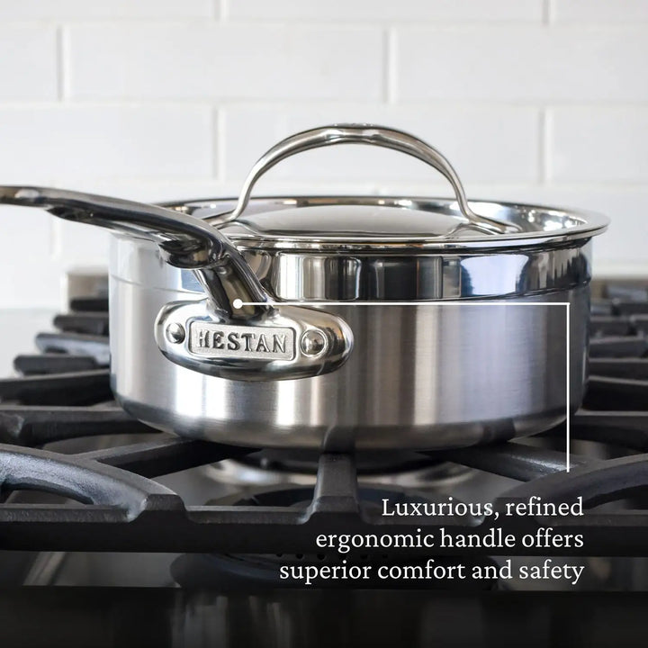 A luxurious stainless steel saucepan with a TITUM® Nonstick finish rests on a gas stovetop, showcasing ProBonds ergonomic handle for comfort and safety. The iconic ProBond plaque gleams against the white tiled backsplash, highlighting the excellence of ProBond cookware.