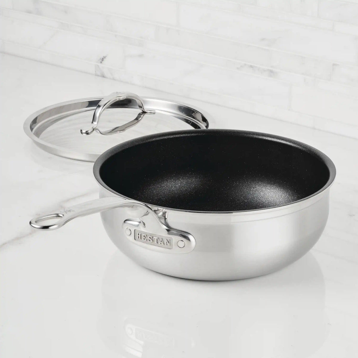 A ProBond® Forged™ Professional Clad Stainless Steel TITUM® Nonstick Essential Pan with Cover, 3.5-Quart, sits on a white marble countertop; its polished handle and lid display the engraved ProBond name.
