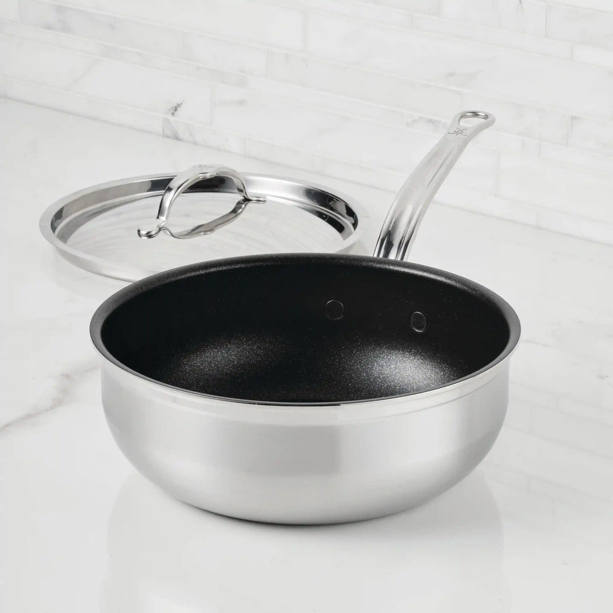 A ProBond® Forged™ Professional Clad Stainless Steel TITUM® Nonstick Essential Pan, 3.5-Quart, is shown on a white countertop with a long handle and its matching stainless steel cover placed beside it.