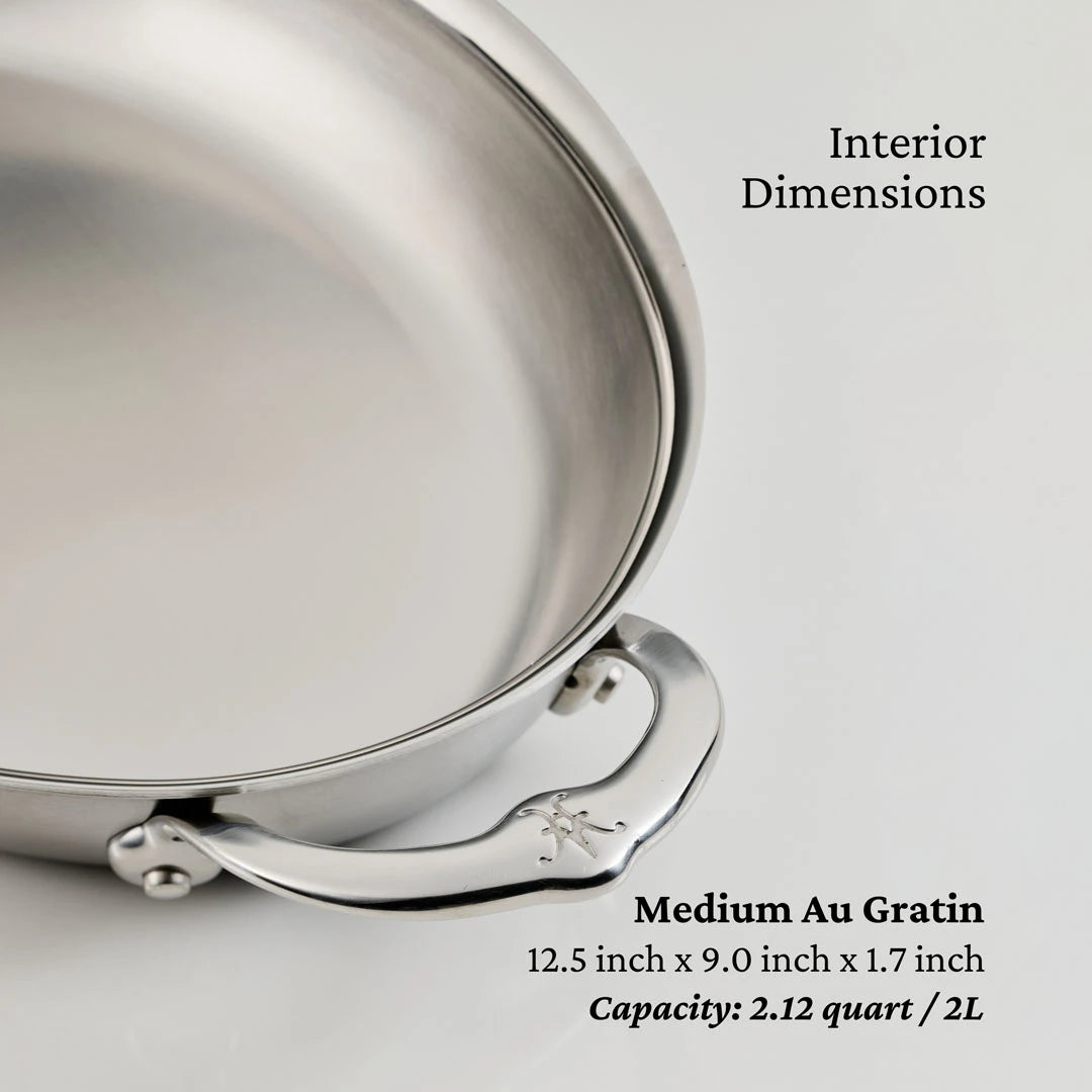 A close-up of the Hestan Provisions 15-Inch x 9-Inch Oval Au Gratin baker highlights its handle and interior, showing text with its size and ample capacity for versatile baking.