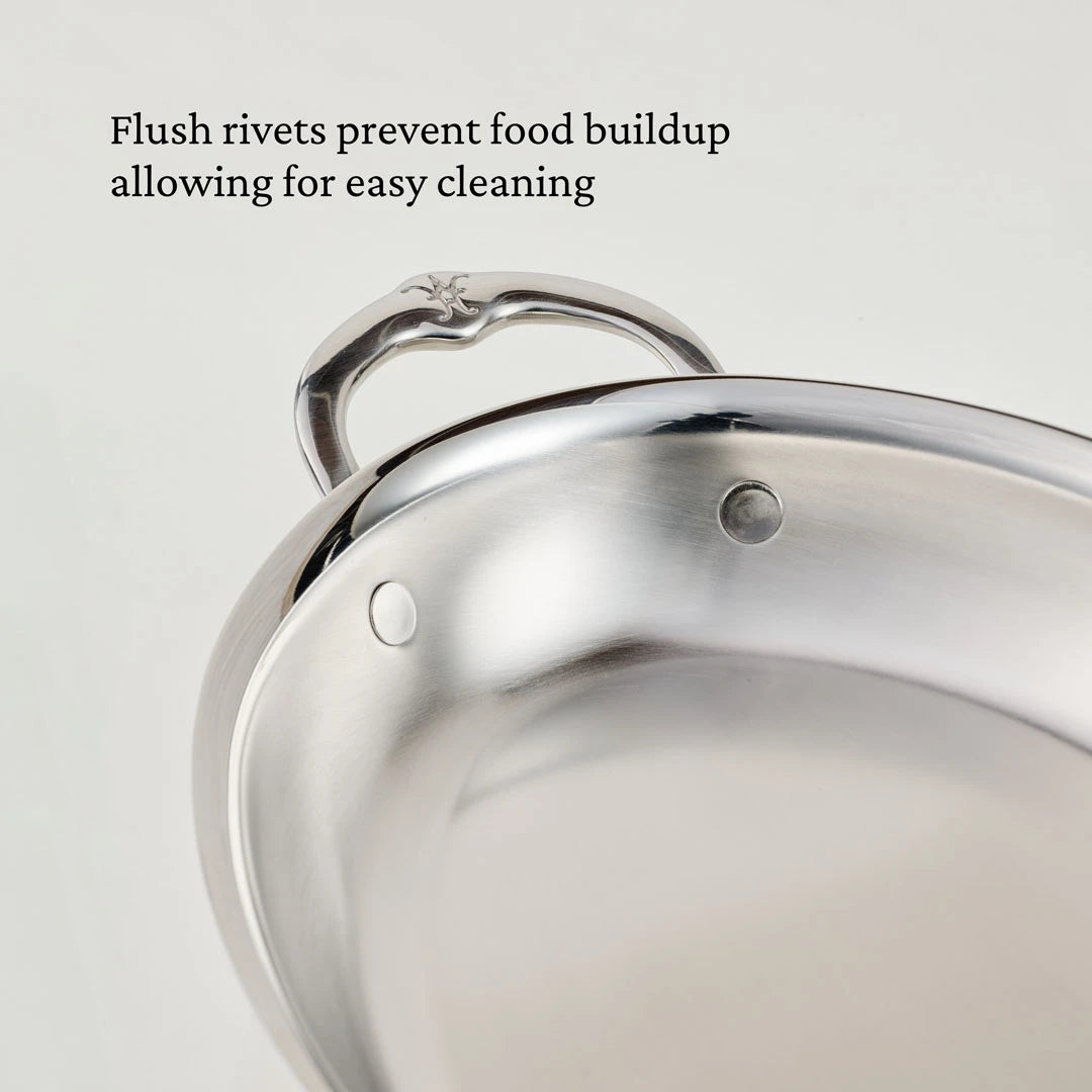Close-up of a Hestan Provisions 15-Inch x 9-Inch Oval Au Gratin baker with stainless steel and flush rivets on the handle and interior. Text on the image reads, Flush rivets prevent food buildup for easy cleaning.