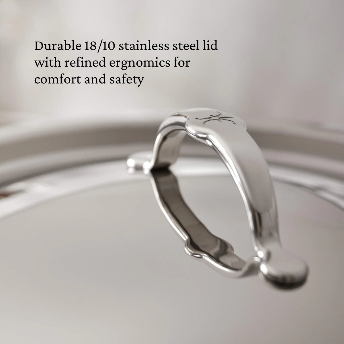 Close-up of a ProBond® Luxe™ Polished Clad Stainless Steel Ultimate Set lid, featuring an arched handle and 18/10 stainless steel. Expert Italian craftsmanship ensures ergonomic comfort and safety—ideal for any cookware collection.