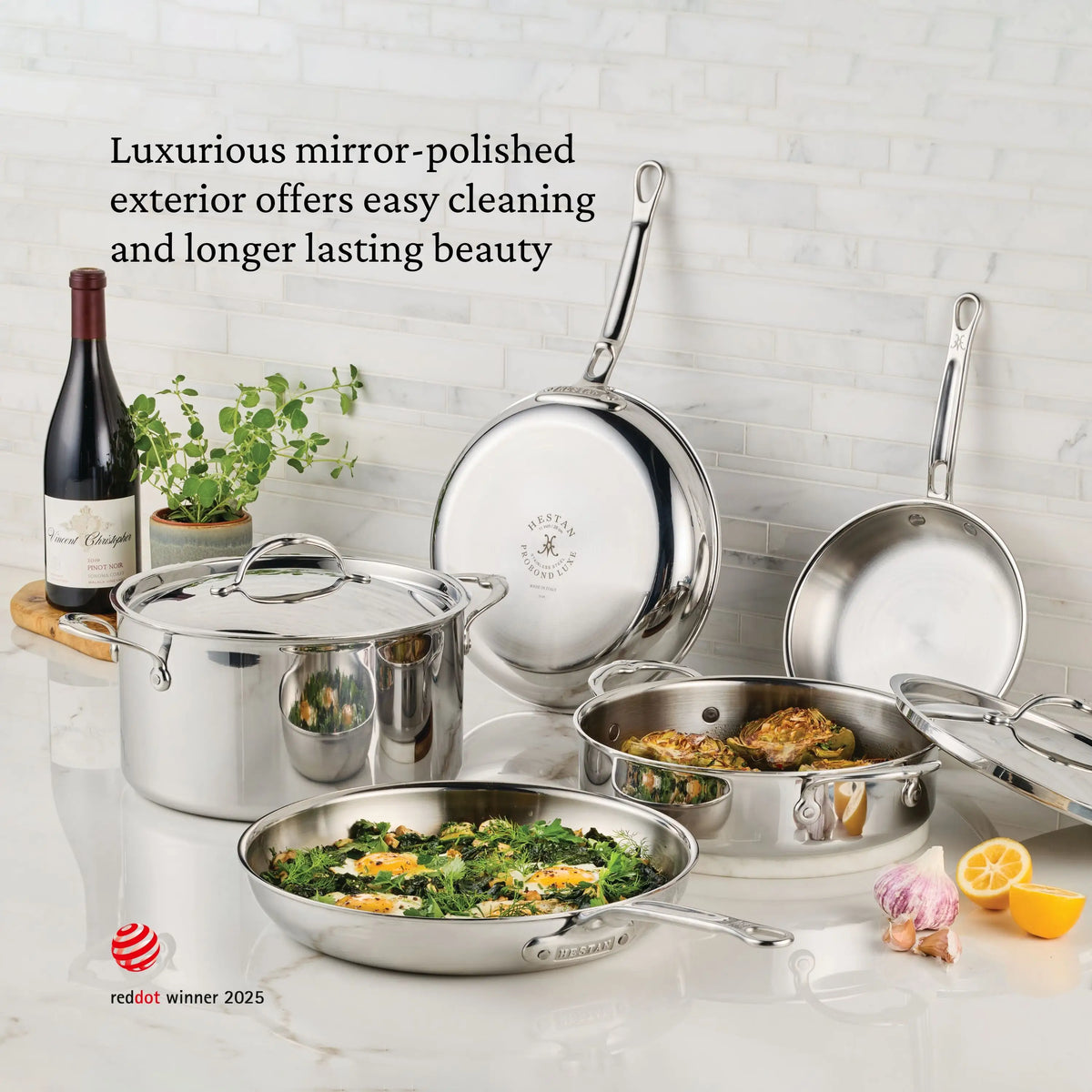 The ProBond® Luxe™ Professional Clad Stainless Steel Soup Pot with Lid shines on a marble countertop beside herbs, a lemon, and wine—highlighting Italian craftsmanship and lasting durability.