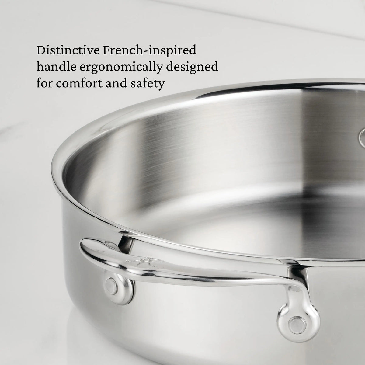 A close-up of the ProBond® Luxe™ Polished Clad Stainless Steel Braiser with Lid, 3.5-Quart, highlights its French-inspired ergonomic handle for comfort and safety in professional cookware design.