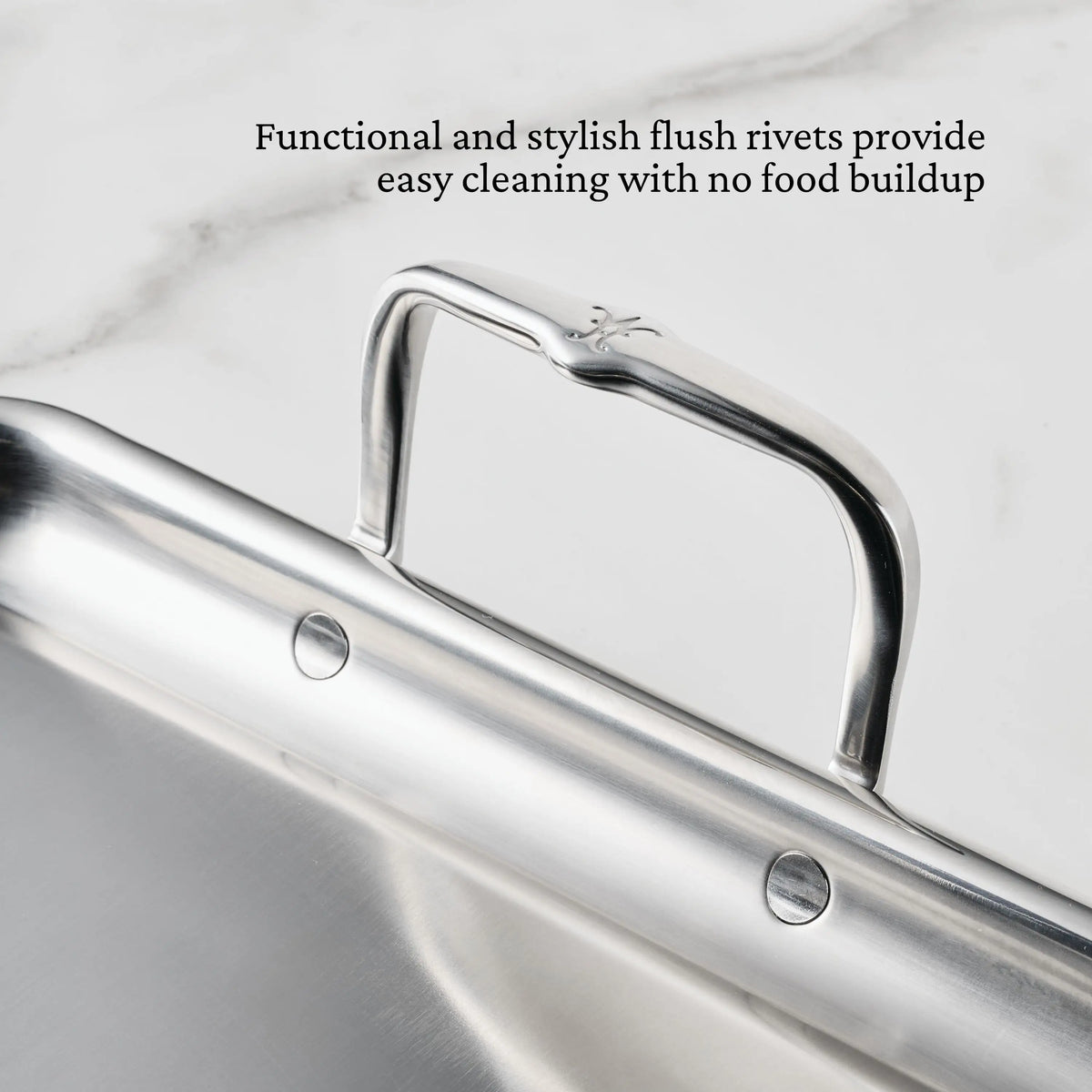 Close-up of the Hestan Provisions Double Burner Griddle’s stainless steel handle with flush rivets on marble. The flush rivets ensure easy cleaning and sleek style, just like premium cookware known for durability and even heat distribution.