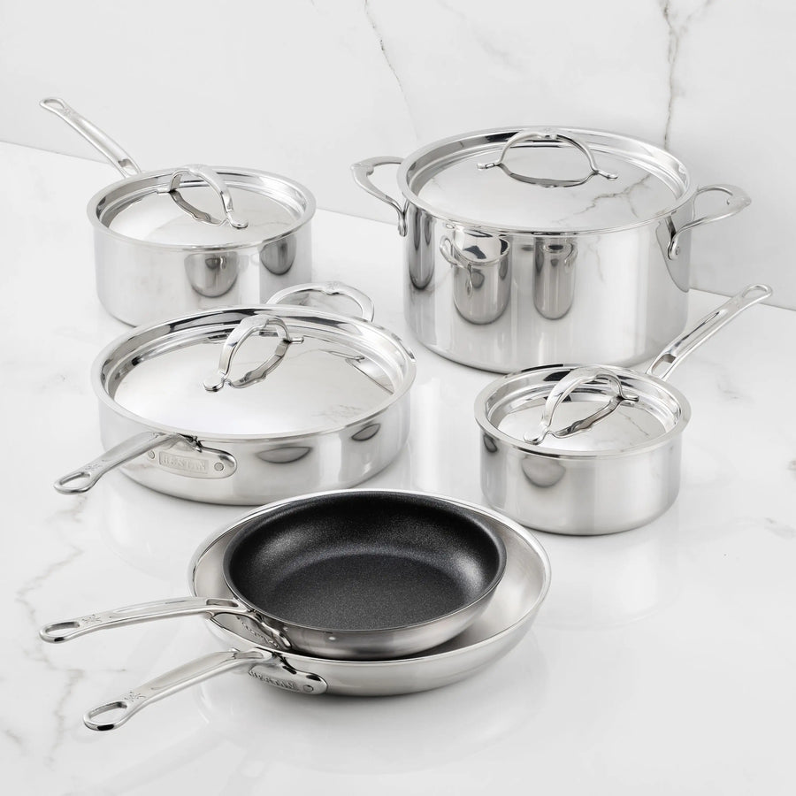 The ProBond® Luxe™ Polished Clad Stainless Steel Premiere Set, 10-Piece, showcases Italian craftsmanship with saucepans, a stockpot, sauté pan, frying pan, and nonstick skillet—each with metal handles and lids—arranged on white marble.