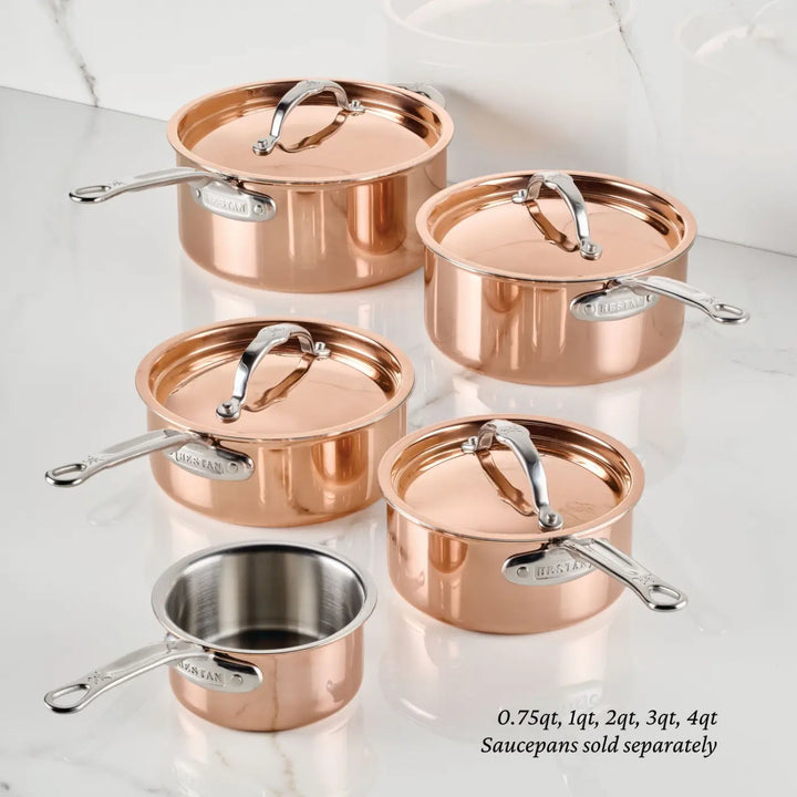 Five Polished Copper Saucepans with Lid from the CopperBond® Aura™ collection, each equipped with sturdy metal handles and lids, are arranged on a white countertop. Every saucepan boasts a durable stainless steel interior and is available in a different size, ranging from 0.75 to 4 quarts. Text indicates that these CopperBond® Aura™ copper cookware pieces are sold separately.