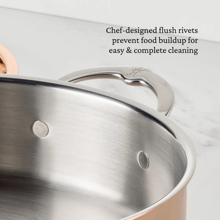 A close-up of a Polished Copper Stock Pot with Lid by CopperBond® Aura™ shows metal flush rivets on the stainless steel interior. Text on the image reads, Chef-designed flush rivets prevent food buildup for easy & complete cleaning. The handle and part of the rim are also visible, highlighting the quality craftsmanship found in premium copper cookware.