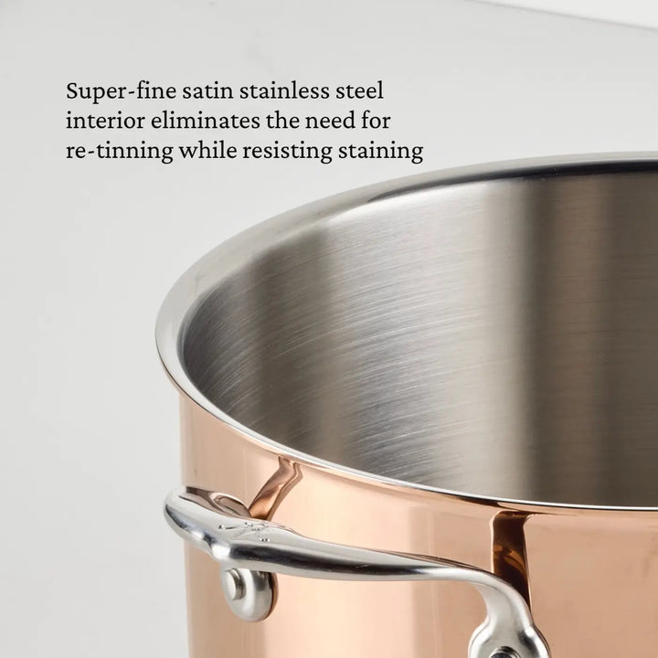 A close-up of the CopperBond® Aura™ Polished Copper Stock Pot with Lid showcases its lustrous copper exterior and satin stainless steel interior. The gleaming finish and robust handle emphasize the durability of this cookware, while on-image text highlights how the satin stainless steel interior makes these Polished Copper Stock Pots both elegant and practical additions to any kitchen.