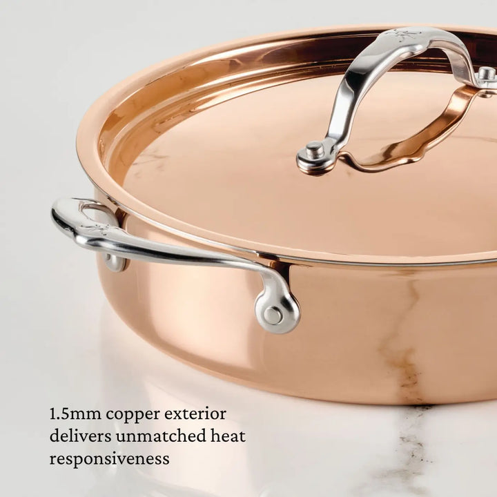 A close-up shows the Polished Copper Saute Pan with Lid from CopperBond® Aura™, featuring stainless steel handles. Text on the image reads, “The 1.5mm copper exterior delivers unmatched heat responsiveness, while the durable stainless steel interior ensures easy cleaning—exemplifying Italian copper cookware quality.”.