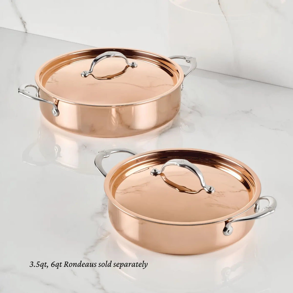Two Polished Copper Rondeaus with stainless steel handles and lids from the CopperBond® Aura™ collection rest on a white marble surface. Each piece, crafted for exceptional quality, features a durable stainless steel interior for effortless cleaning. The text in the image notes: 3.5qt and 6qt Polished Copper Rondeaus with Lid are sold separately.