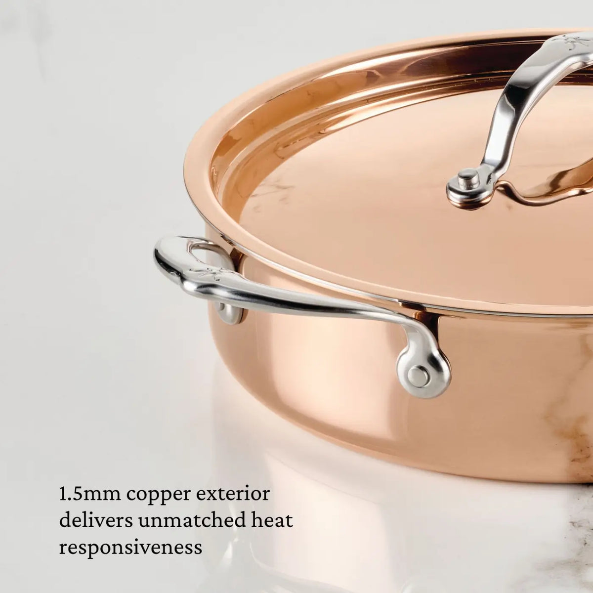 A close-up of the CopperBond® Aura™ Polished Copper Rondeaus with Lid, featuring a stainless steel handle and lid on a marble surface, showcases the superior quality of copper cookware. Text on the image reads: 1.5mm copper exterior delivers unmatched heat responsiveness.