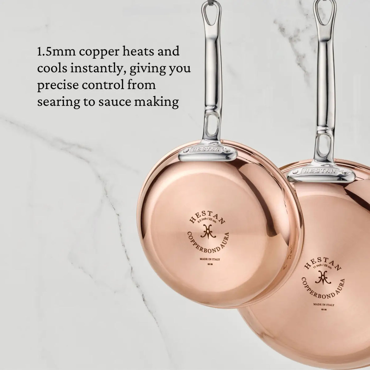 Two polished copper CopperBond® Aura™ skillets with stainless steel handles are shown against a marble background. This professional-grade cookware features a 1.5mm copper body for precise temperature control, complemented by a durable stainless steel interior for exceptional performance and easy cleanup.