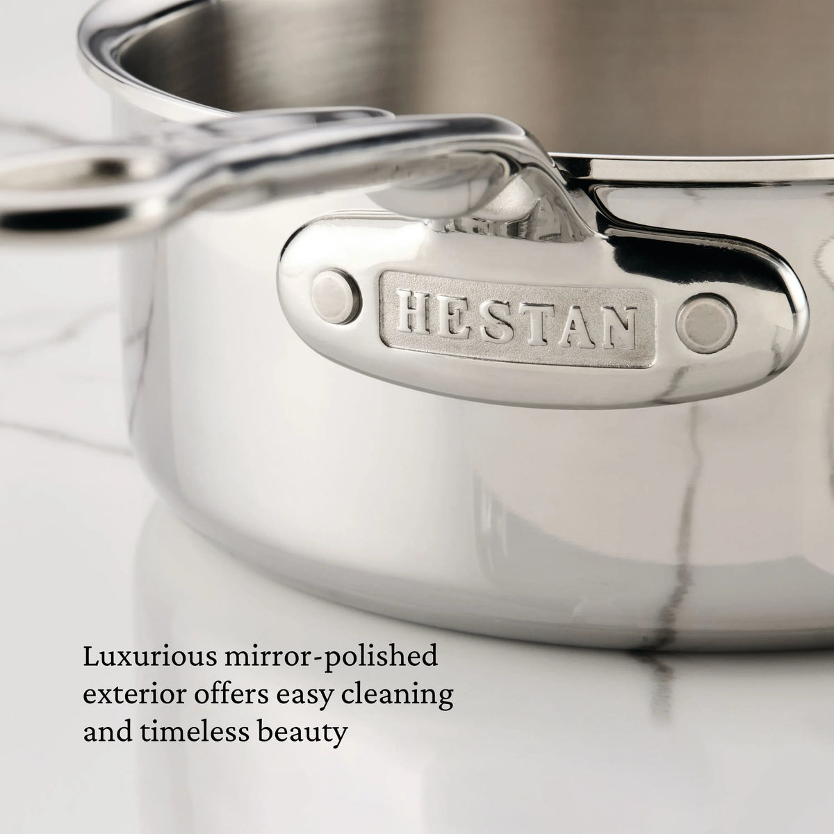 Close-up of the ProBond® Luxe™ Polished Clad Stainless Steel Signature Set, 5-Piece with a mirror-polished finish. Easy to clean, beautifully timeless, and suitable for induction cooking. Brand name embossed on handle.
