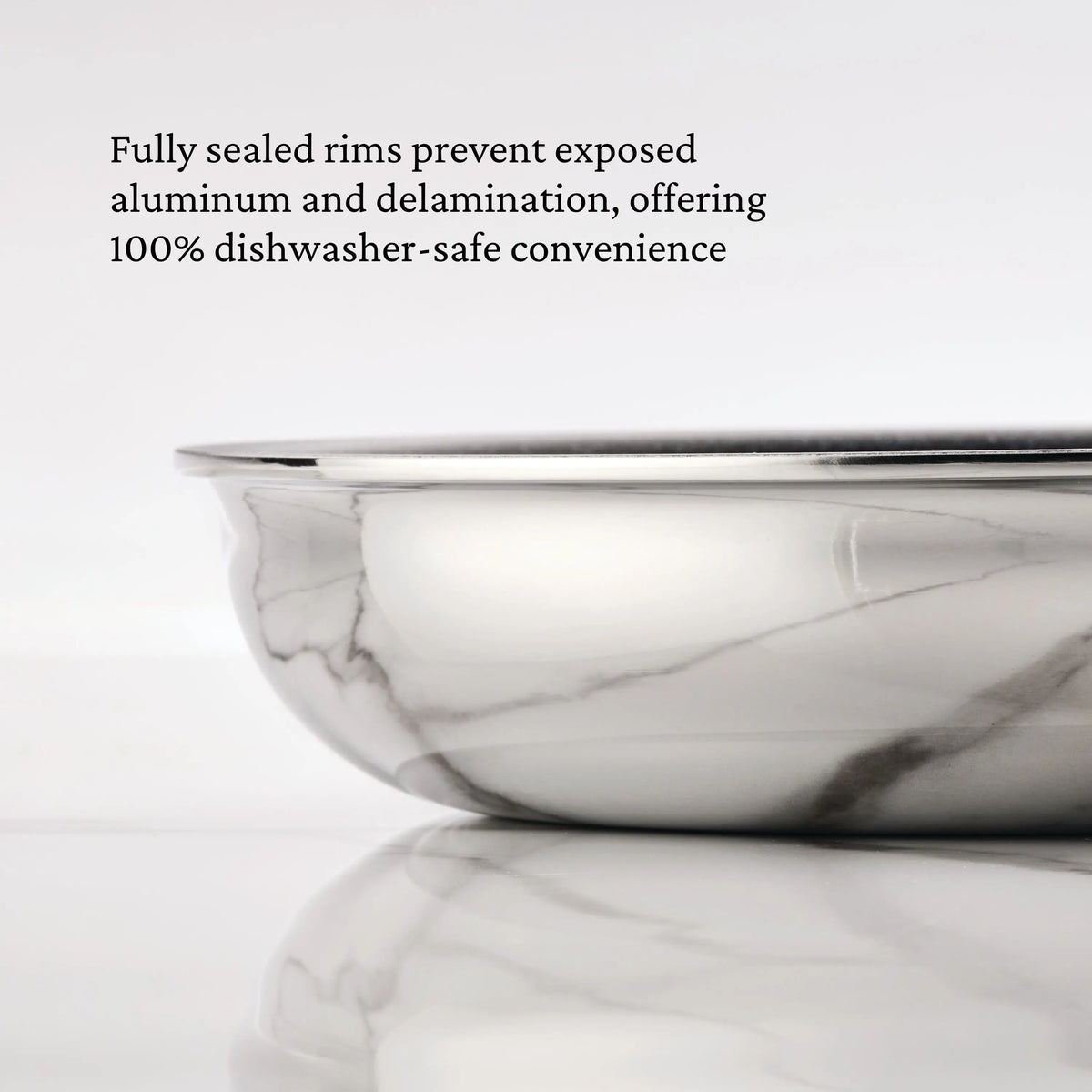 A close-up of the ProBond® Luxe™ Polished Clad Stainless Steel Signature Set, 7-Piece, shows its shiny sealed rim on marble, highlighting how this tri-ply clad cookware stays durable and dishwasher-safe by preventing exposed aluminum.