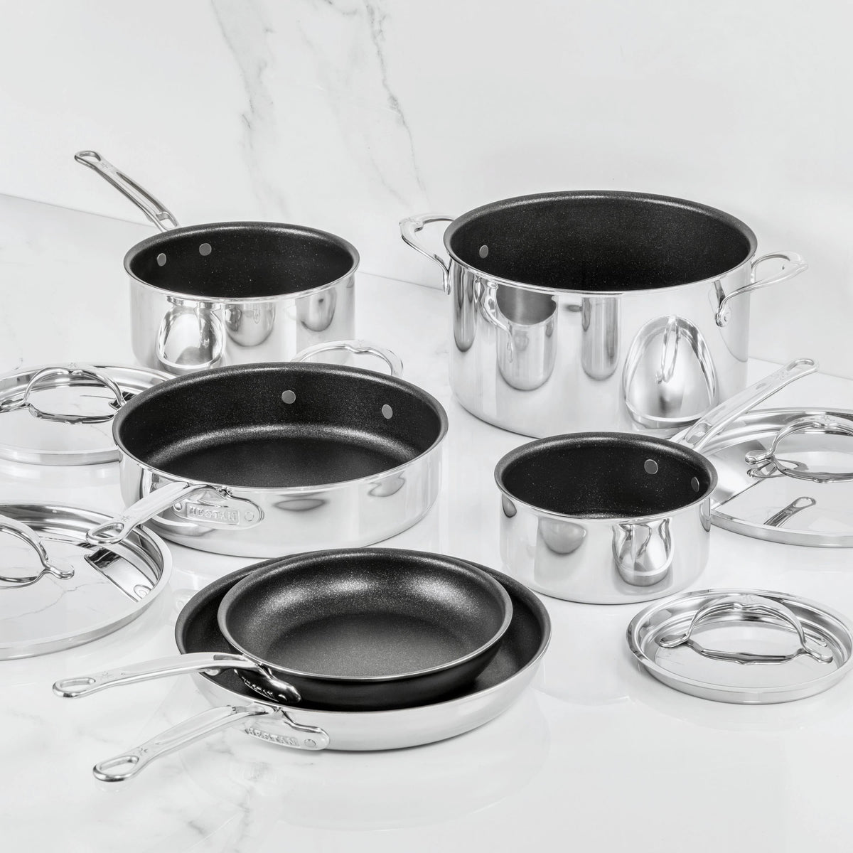 A 10-piece set of ProBond Luxe® Polished Clad Stainless Steel cookware featuring TITUM® nonstick interiors, including an assortment of saucepans, frying pans, and a stockpot—each with its own matching lid—beautifully displayed on a white marble surface.