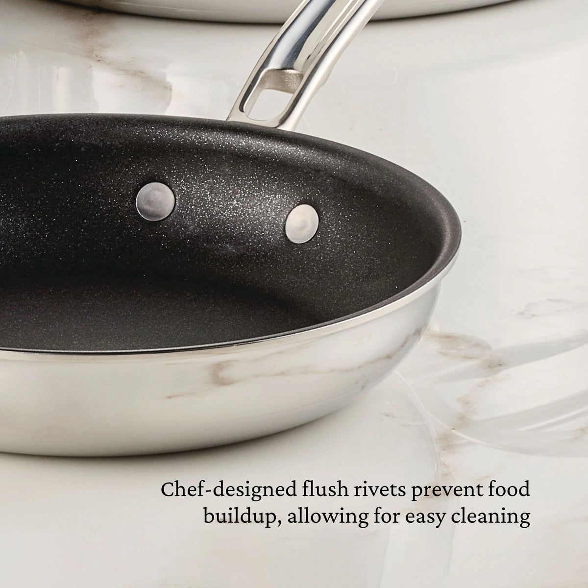 A Polished Clad Stainless Steel 10-Piece Set with TITUM® Nonstick from ProBond Luxe® is shown on a white marble surface. Text below reads, Chef-designed flush rivets prevent food buildup, allowing for easy cleaning.